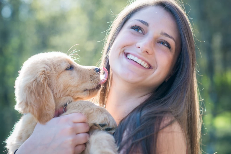 a woman smiling and hugging a small dog