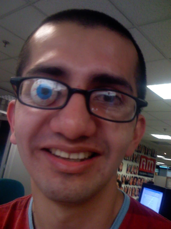 a man with large eyeballs standing in front of a cubicle