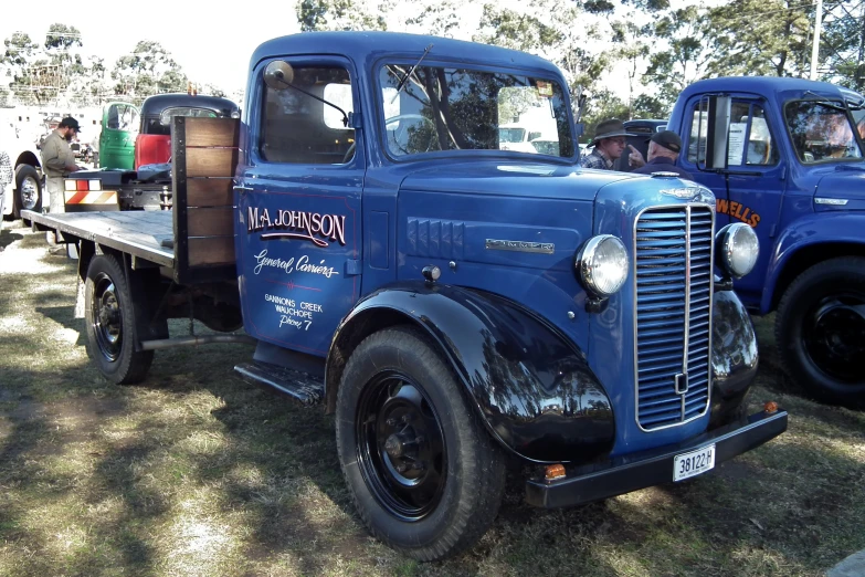 two old fashioned trucks are parked in the dirt