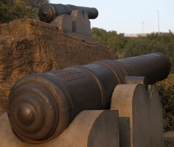 large cannon statue sitting in front of a cliff