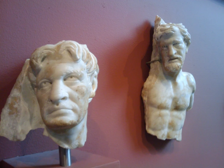 two stone sculptures of busts of men on the wall