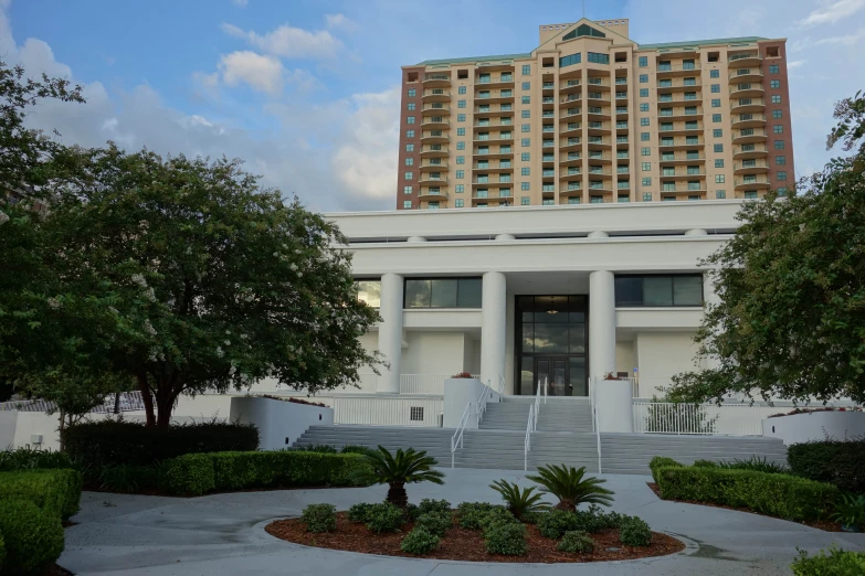 a large building with a lot of windows near trees and shrubs