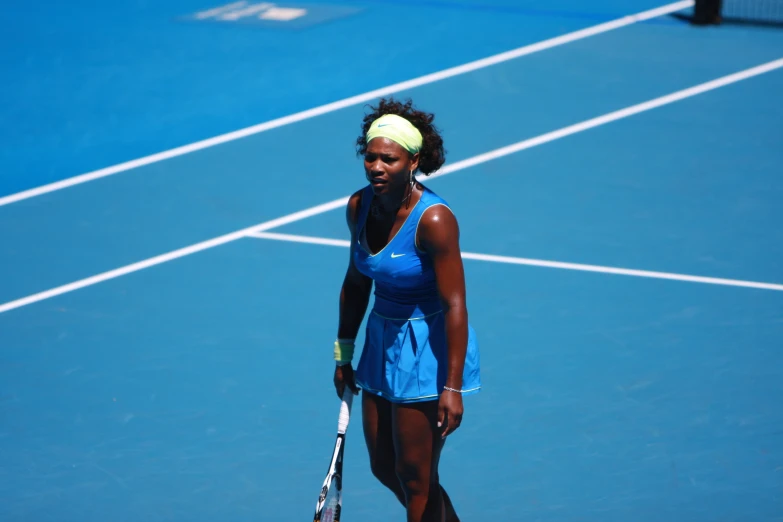 a female tennis player wearing a blue dress holding her racket