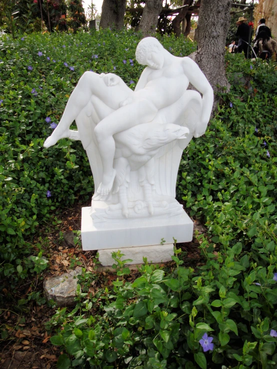 a sculpture sitting in the middle of some green bushes