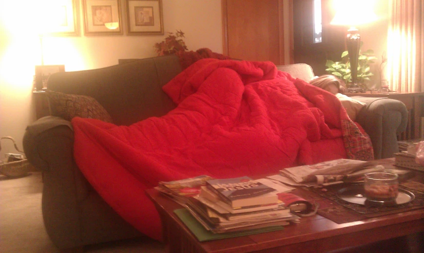 a living room with a red blanket on the couch and a coffee table