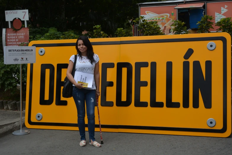 a girl standing beside a large yellow sign