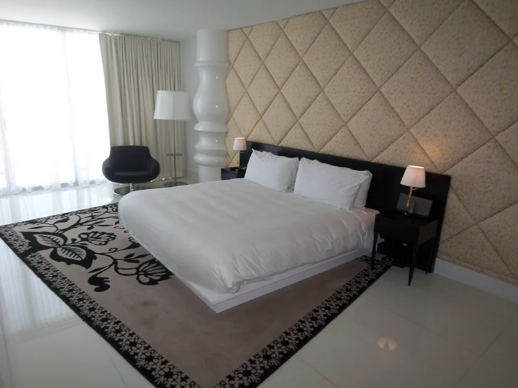 a large white bed sitting next to a window in a bedroom