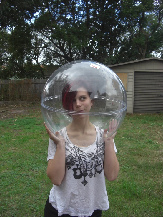  standing in back yard holding up a huge crystal ball