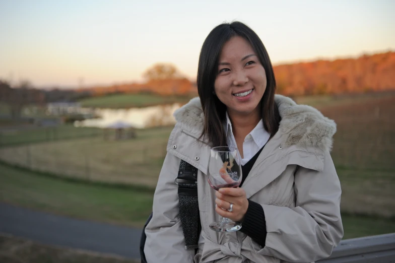 the smiling woman is holding a wine glass