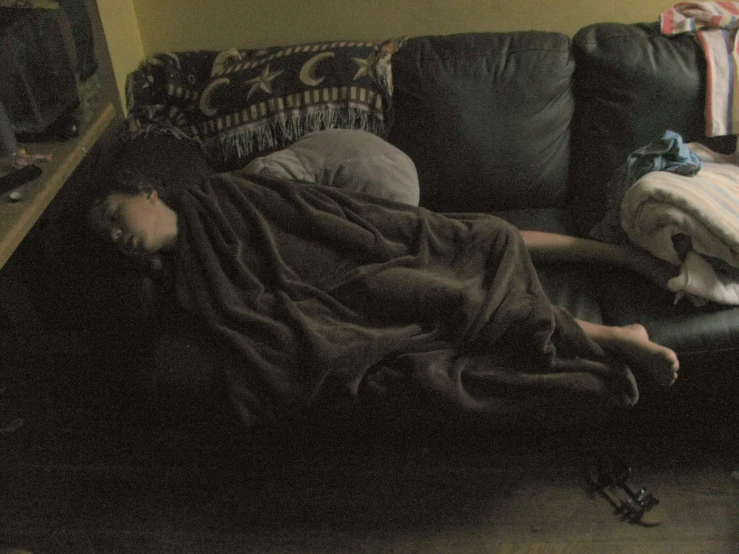 a person lying on a couch covered by blankets