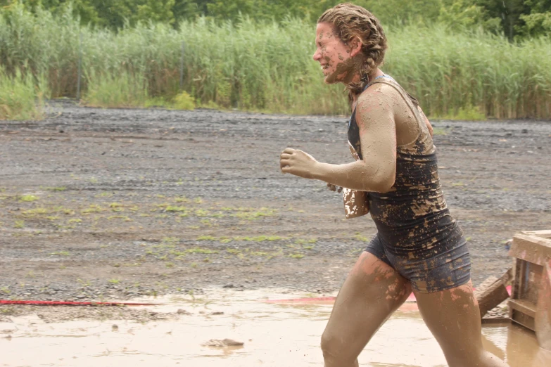 the man wearing mud clothing runs in a river