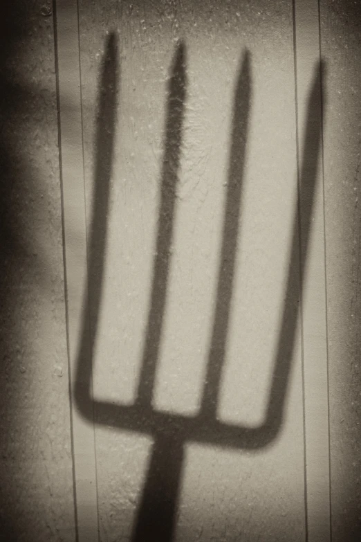 a shadow of a straight knife on a wall