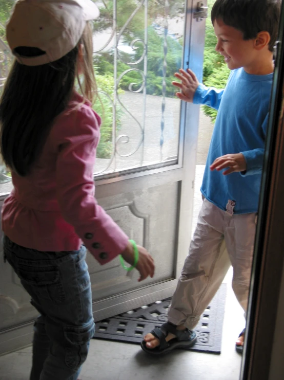 two small children standing outside of a door