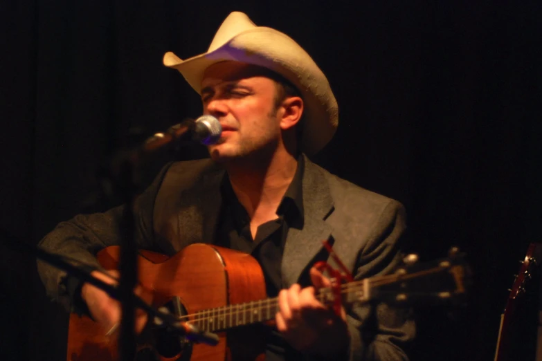 a man is singing into a microphone and playing the guitar