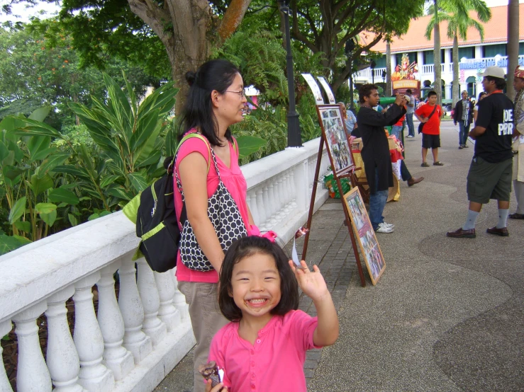 the people are standing by the walkway and paintings