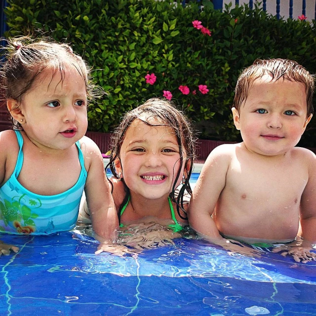 three children in the water of an outdoor swimming pool