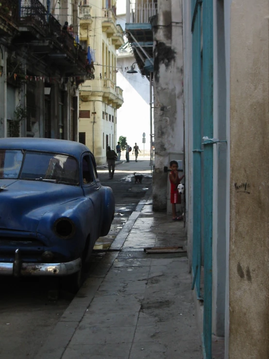 two old fashion cars parked on a very narrow street