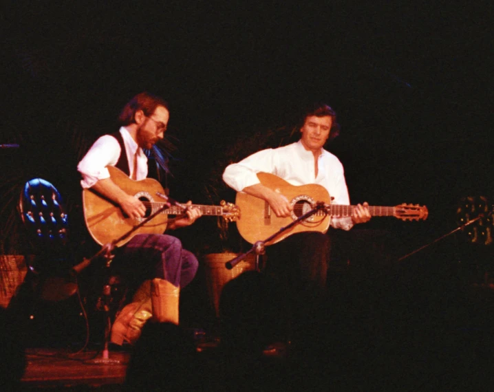 two people that are playing some guitars