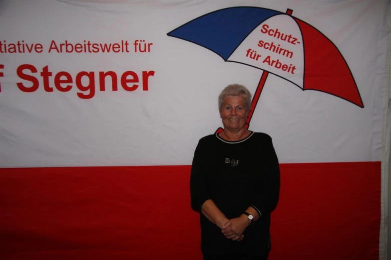 a woman standing in front of a red white and blue banner with an umbrella
