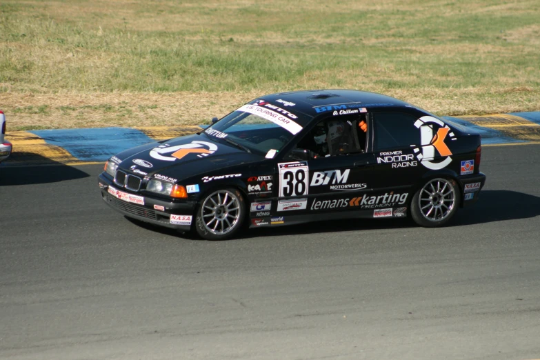 a man driving a black car down the side of a track