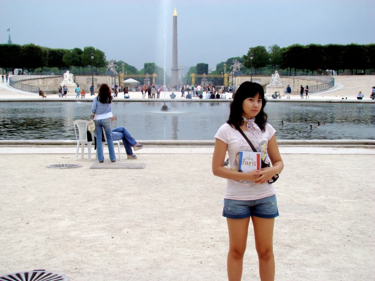 a woman standing in front of a water fountain holding a cell phone