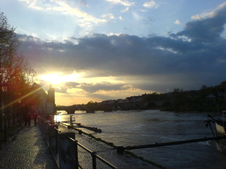 a view of a river at dusk with the sun setting behind