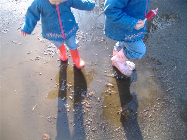 two toddler girls wearing rain boots walk in dles