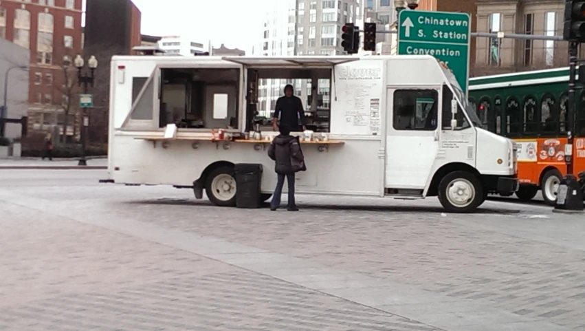 two people standing outside of a white truck