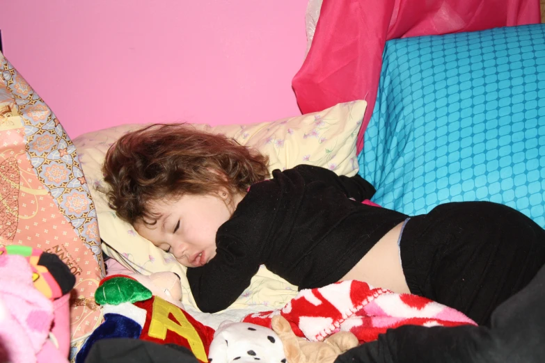 a woman sleeping on top of a bed with stuffed animals