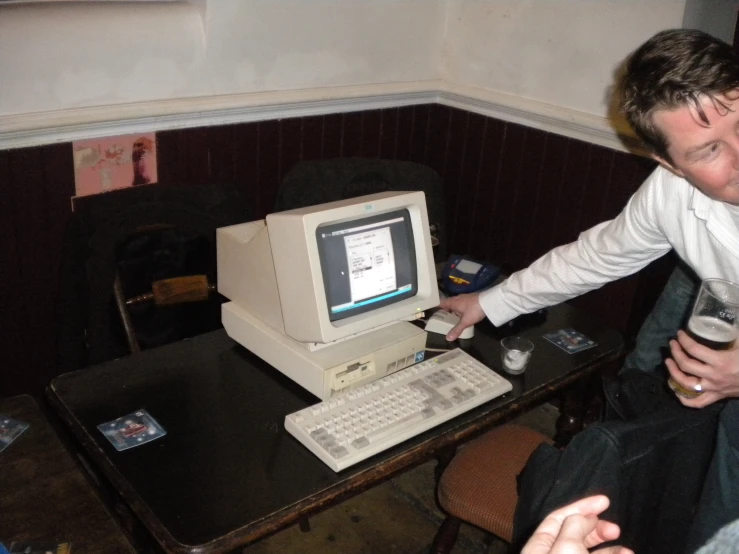 a man sits and laughs as he uses the old computer