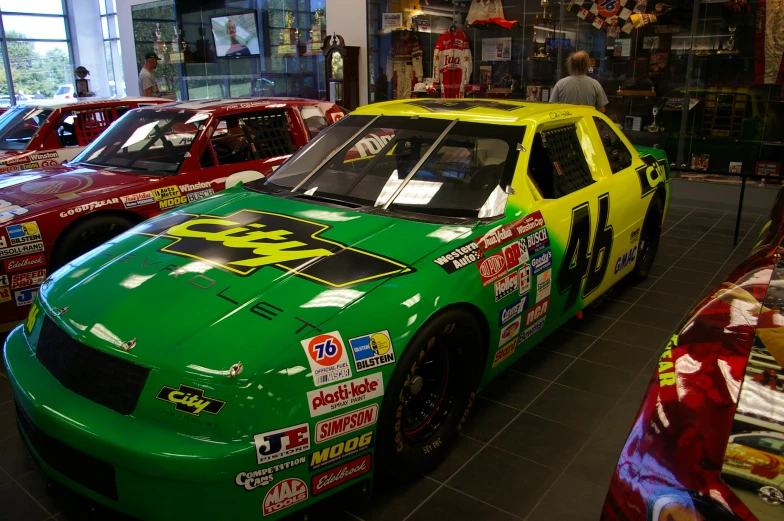 racing cars sit inside of a building during the day