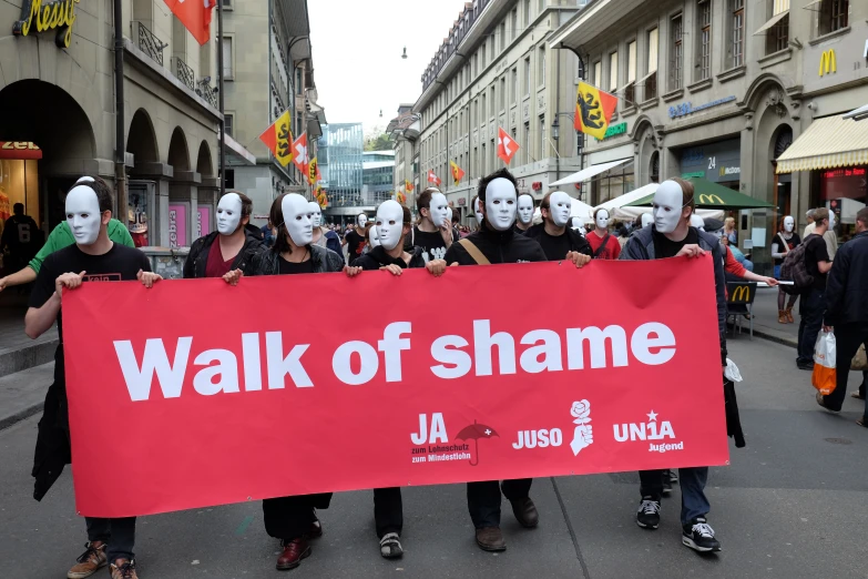 group of people holding a walk of shame sign