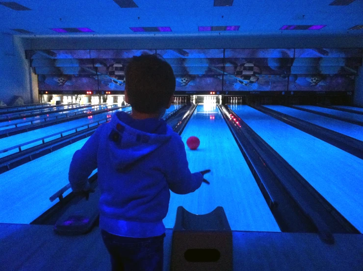 a boy at the bowling alley holding a bowling ball