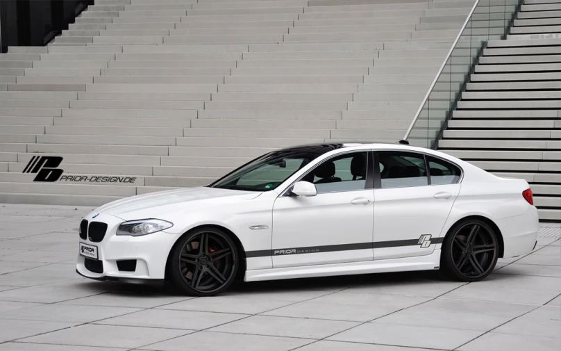 a white bmw car parked next to a staircase