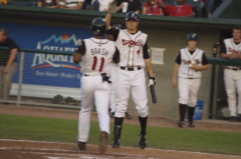 two baseball players giving each other high five on the field