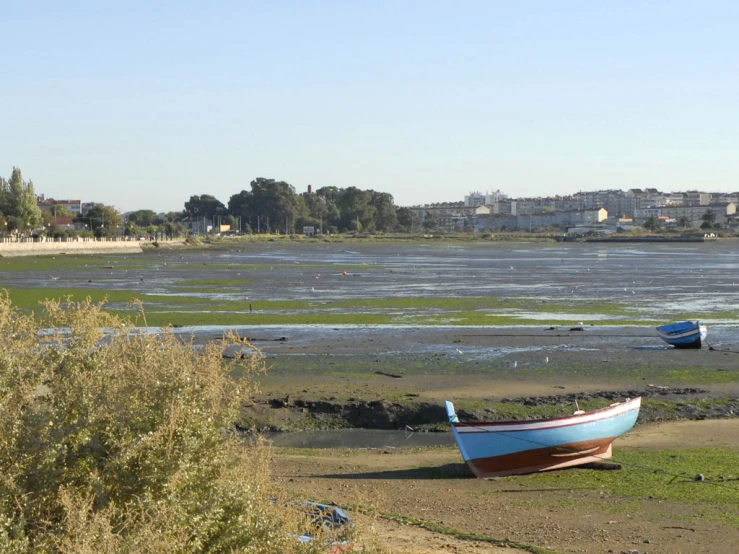 the boats are sitting by the water in the sand