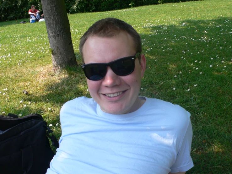 a man smiles while sitting under a tree