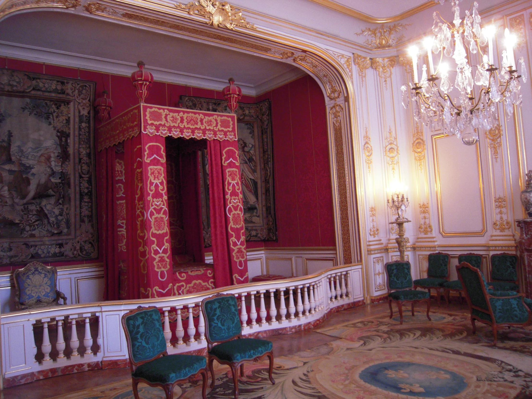 a red room with a red bed, chandelier and four chairs