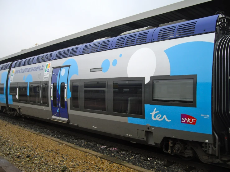 the blue and silver passenger train is pulled up to the station