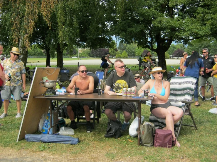 group of people sitting at tables and chairs, under trees