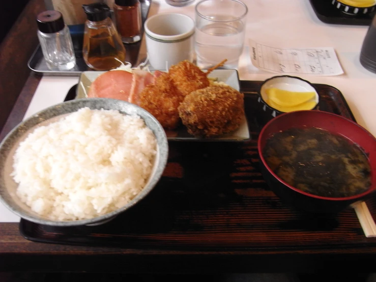 a tray with some rice and chop sticks next to other dishes on it