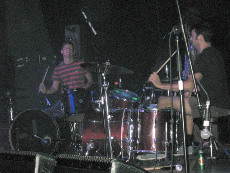 two drummers playing on stage during a concert