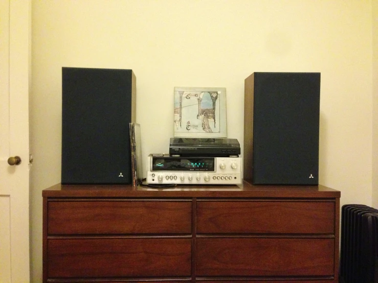 a dresser with speakers on it in front of a painting