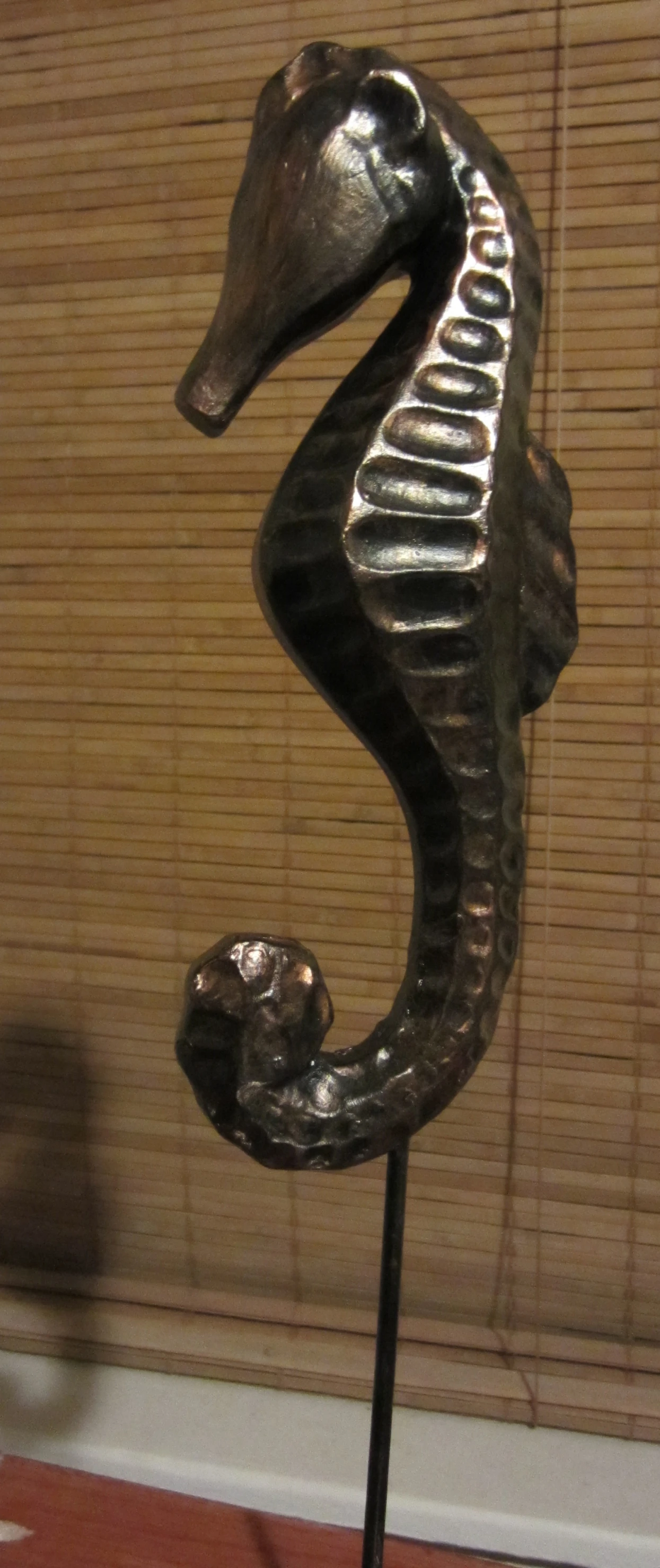 a metal sea horse with a brown striped wall