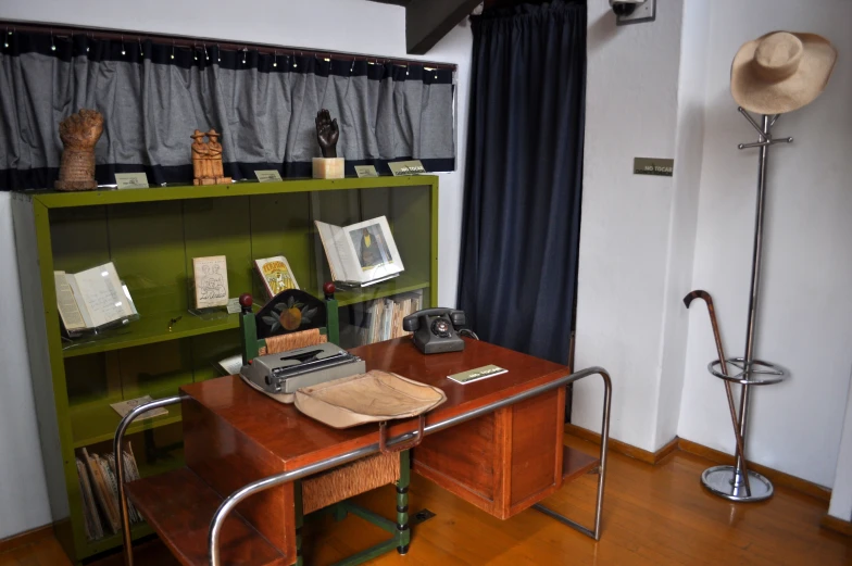 desk with many different objects and books, in a room