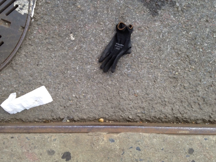 a glove that is sitting on the ground near a sidewalk