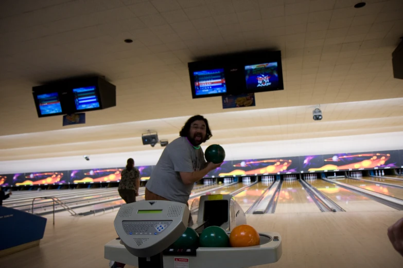 a man holding bowling balls in his right hand and bowling pins at his left