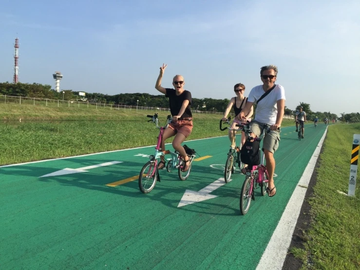 three people riding bicycles and one man hing a stroller