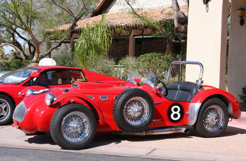 an old fashioned racing car is parked on the side of the road