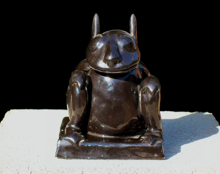 an old statue of a frog sitting in the sun